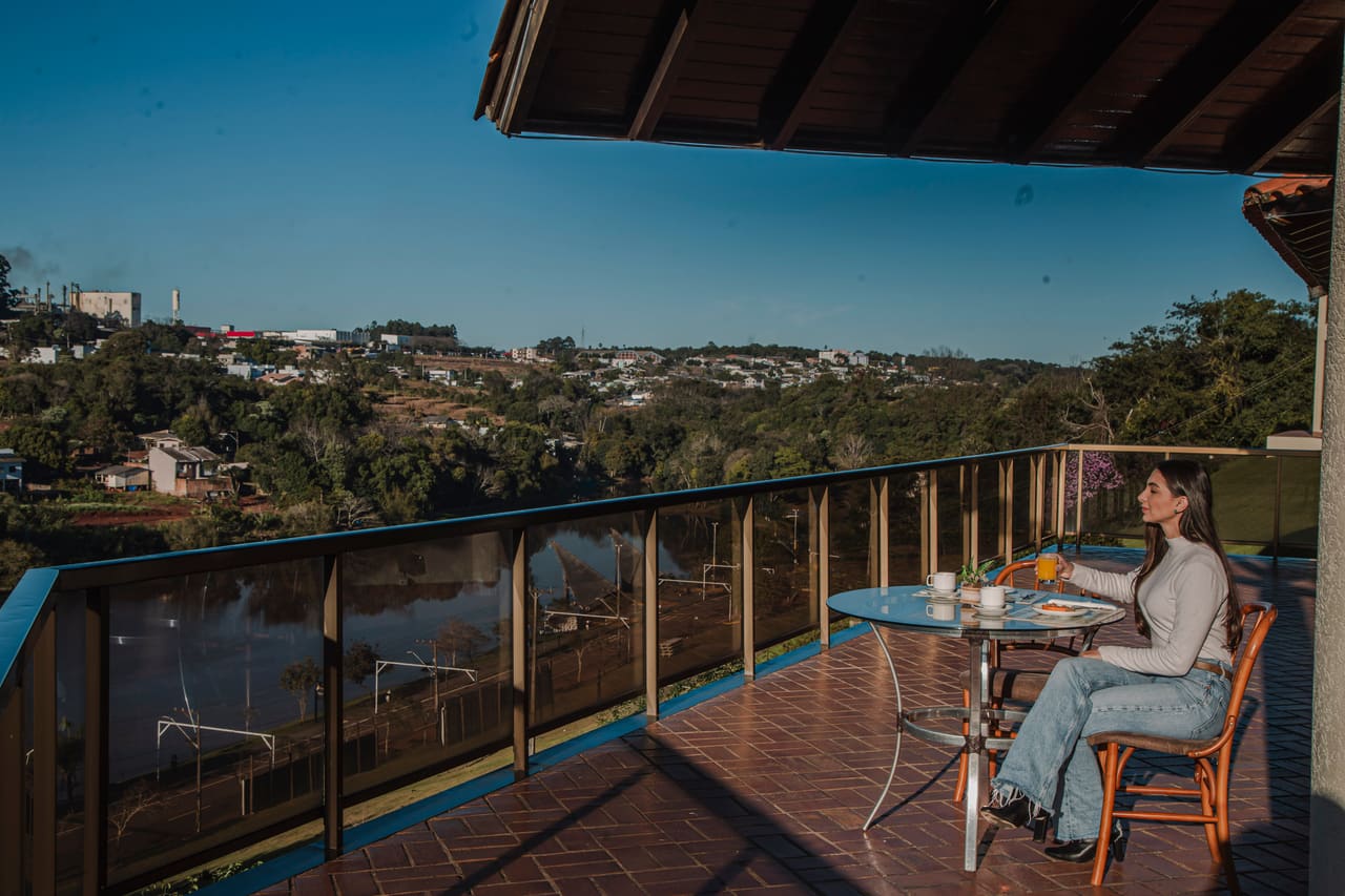 Hóspede tomando café da manhã na varanda com vista para o lago