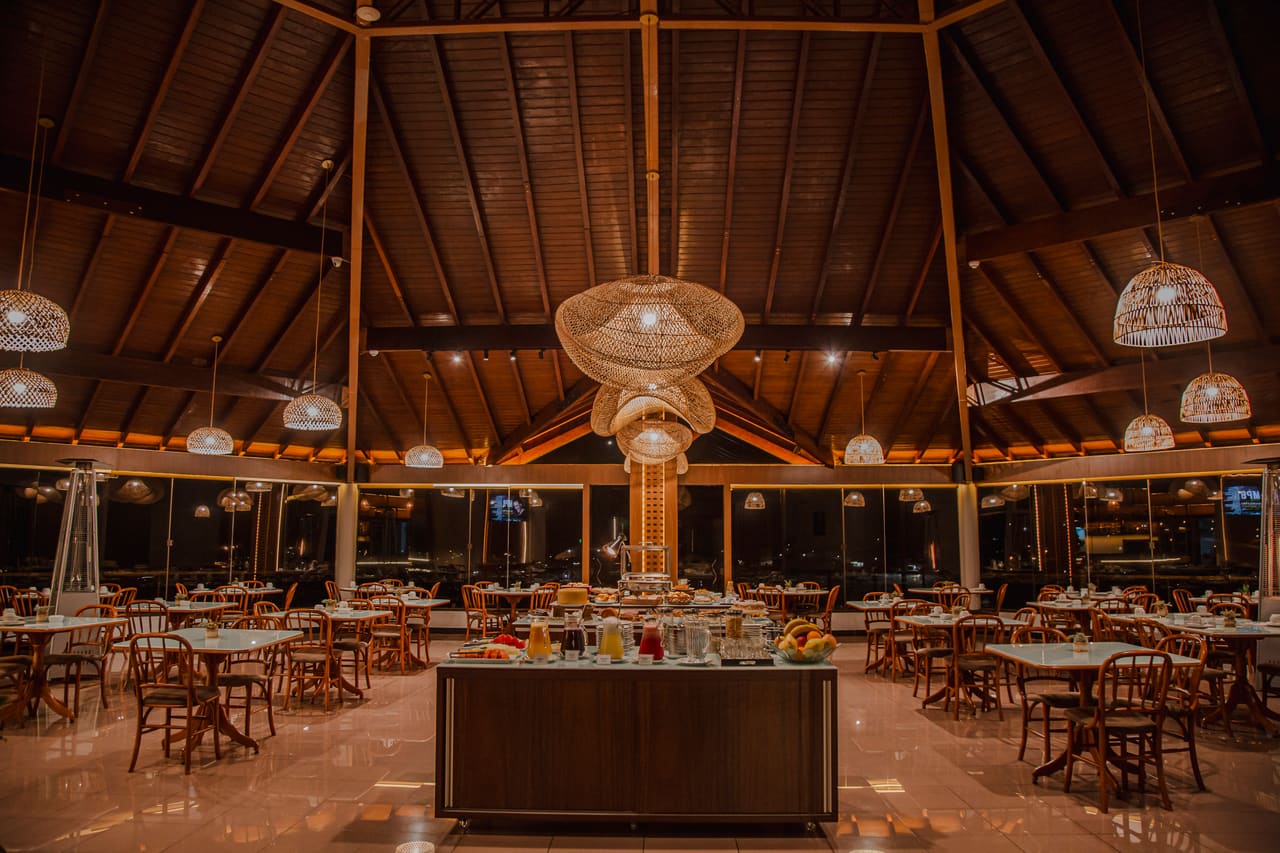 Salão do restaurante do Hotel Lago Dourado com teto de madeira e luminárias de palha